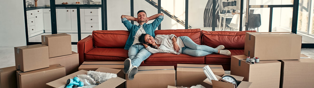 a couple relaxing on sofa with boxes packed