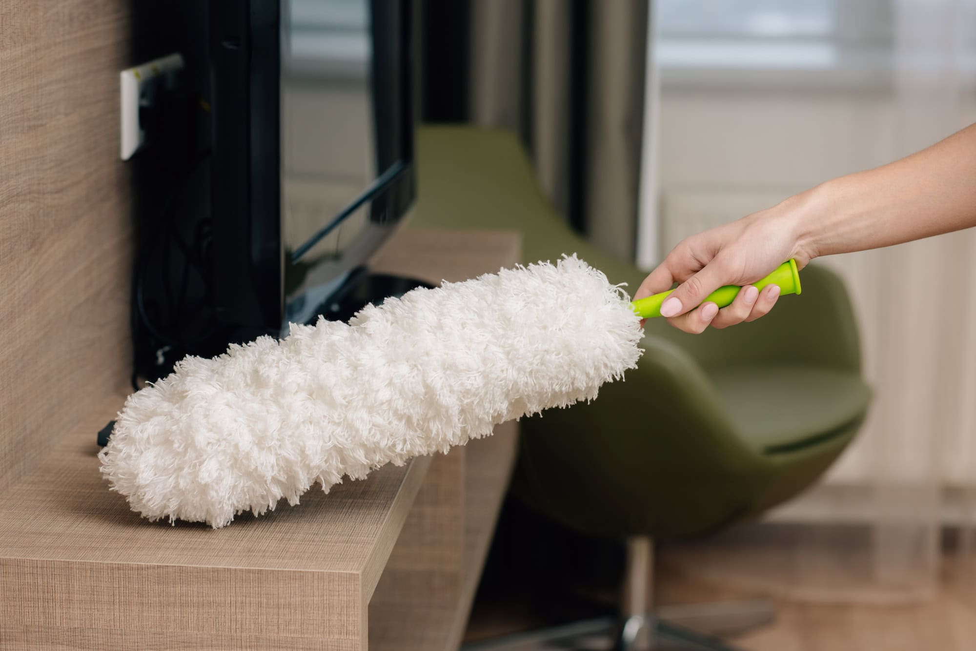 cropped shot of maid cleaning shelf with duster