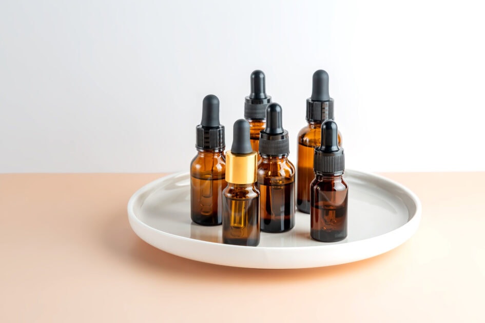dark glass cosmetic bottles dropper with essential oil on a ceramic tray 