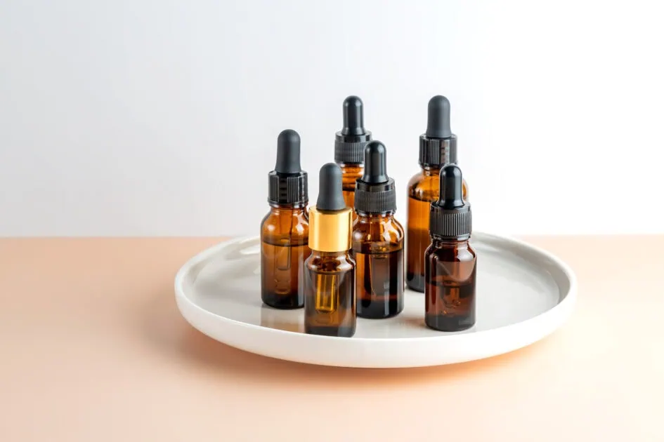 dark glass cosmetic bottles dropper with essential oil on a ceramic tray 