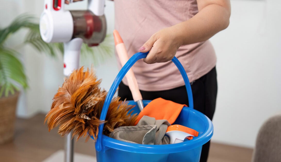 cleaning supplies ready a woman carries a bucket filled with cleaning tools for corners and edges