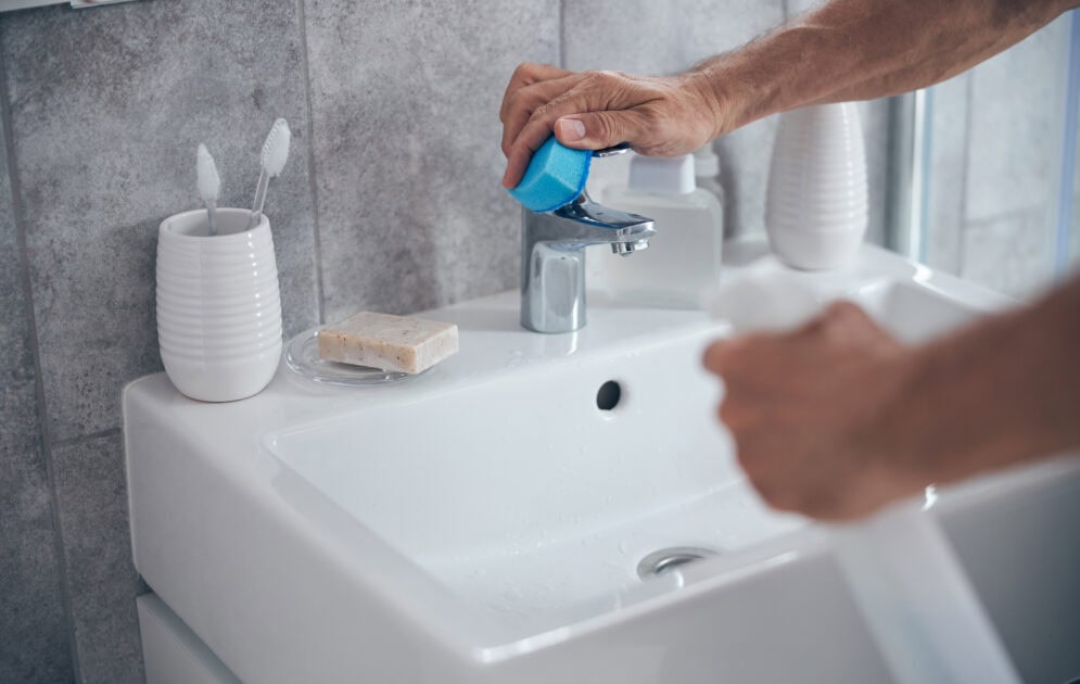wiping bathroom sink tap during weekly clean